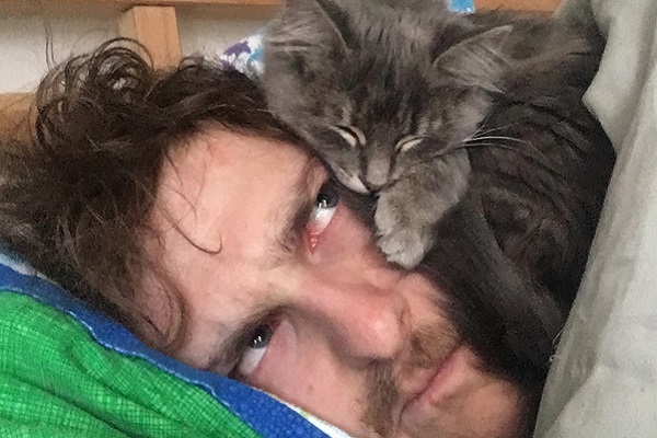 uomo guarda gattino che gli dorme in testa