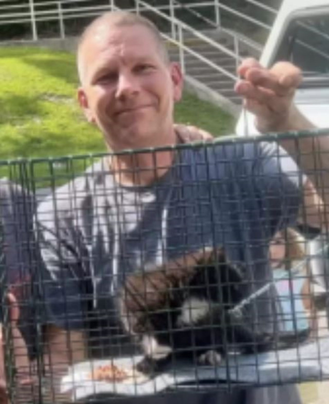Un uomo con un gattino in gabbia